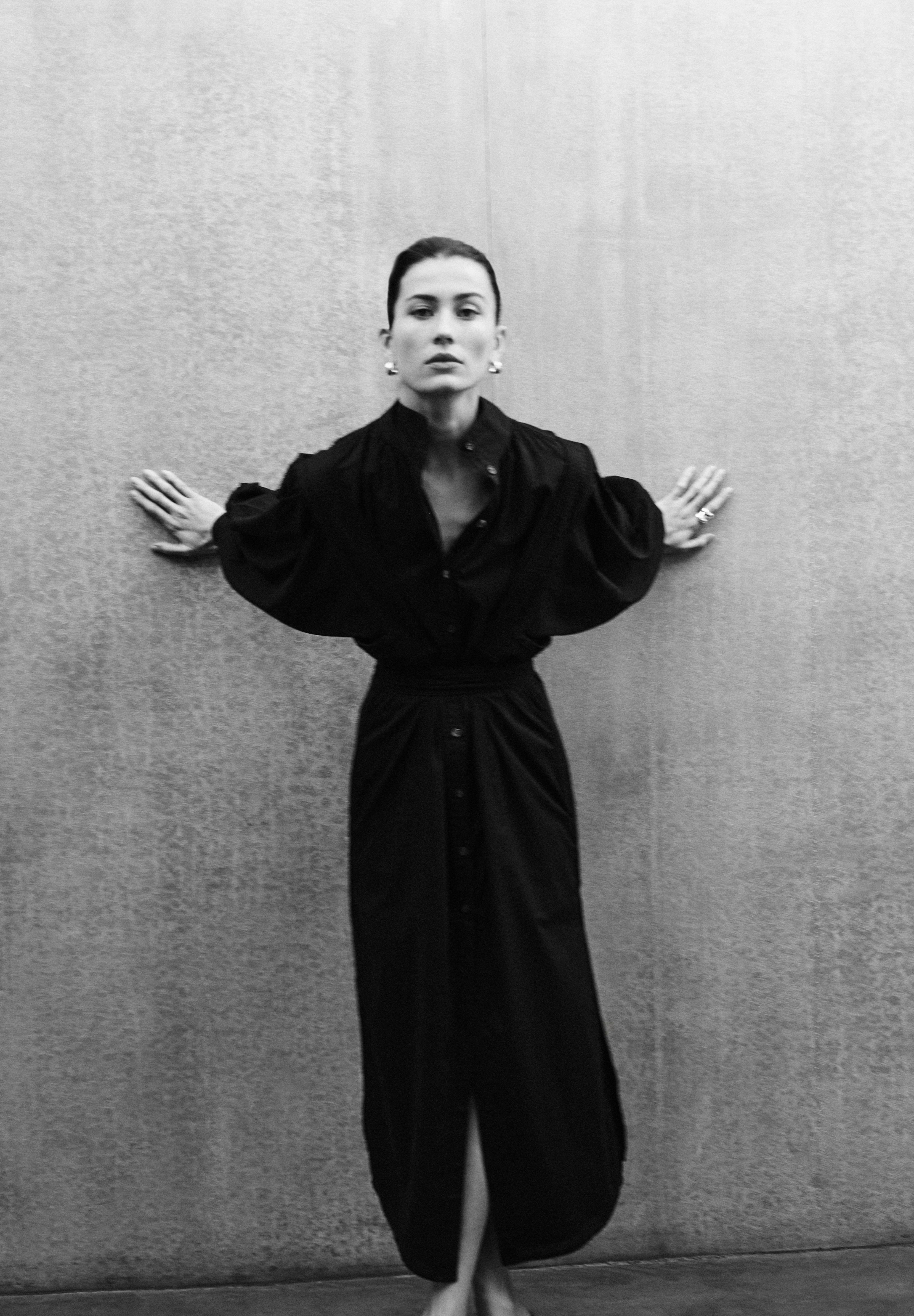 Woman wearing MAY black cotton voile dress with hand-embroidered sculptural sleeves, minimal elegant design