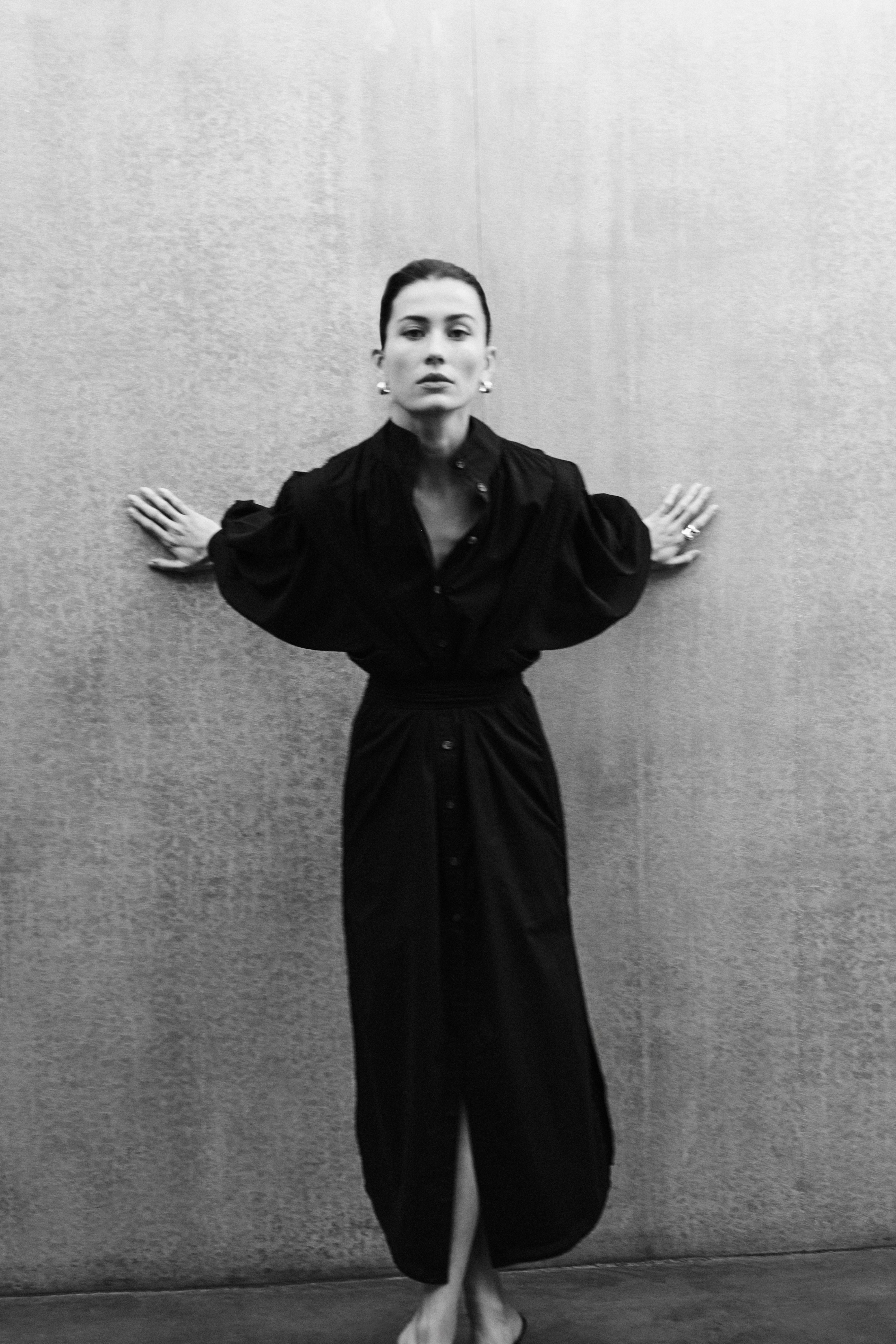 Woman wearing MAY black cotton voile dress with hand-embroidered sculptural sleeves, minimal elegant design
