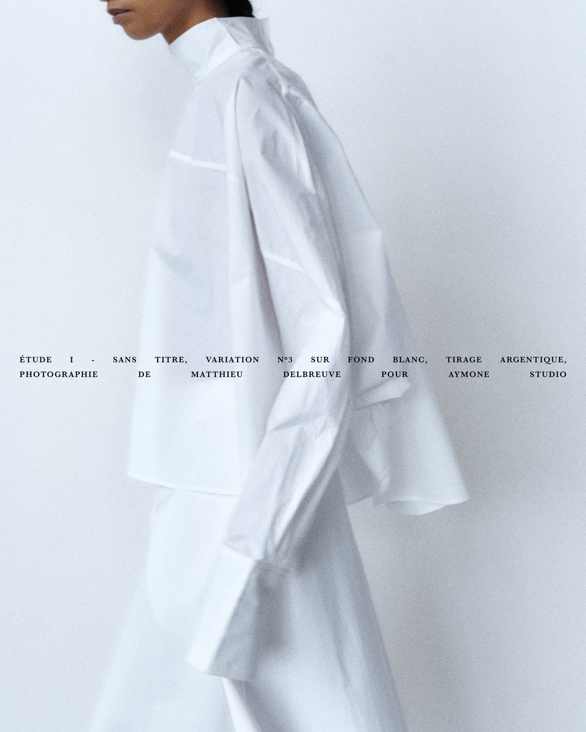 Woman wearing white oversized shirt with sculptural volume, minimalist design against white background