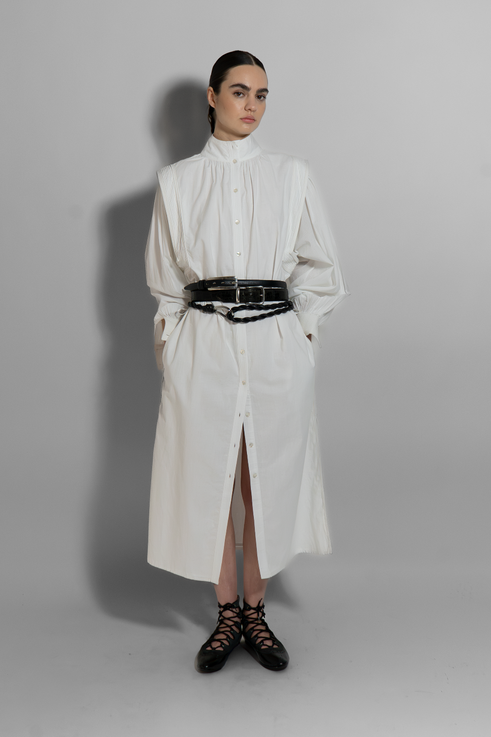 White cotton voile MAY dress with hand-embroidered details, black belt, long sleeves, and architectural cut for modern minimalist style
