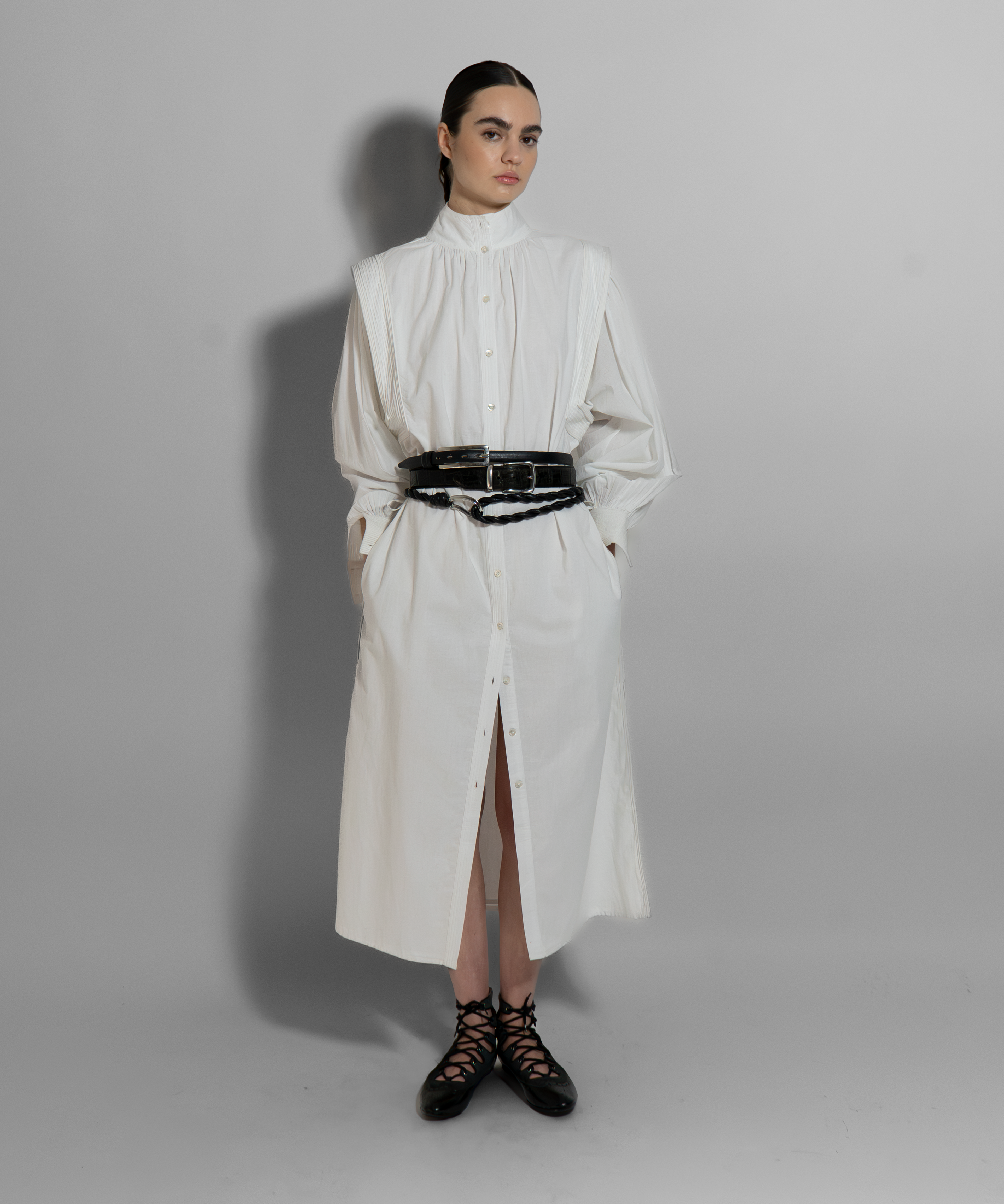White cotton voile MAY dress with hand-embroidered details, black belt, long sleeves, and architectural cut for modern minimalist style