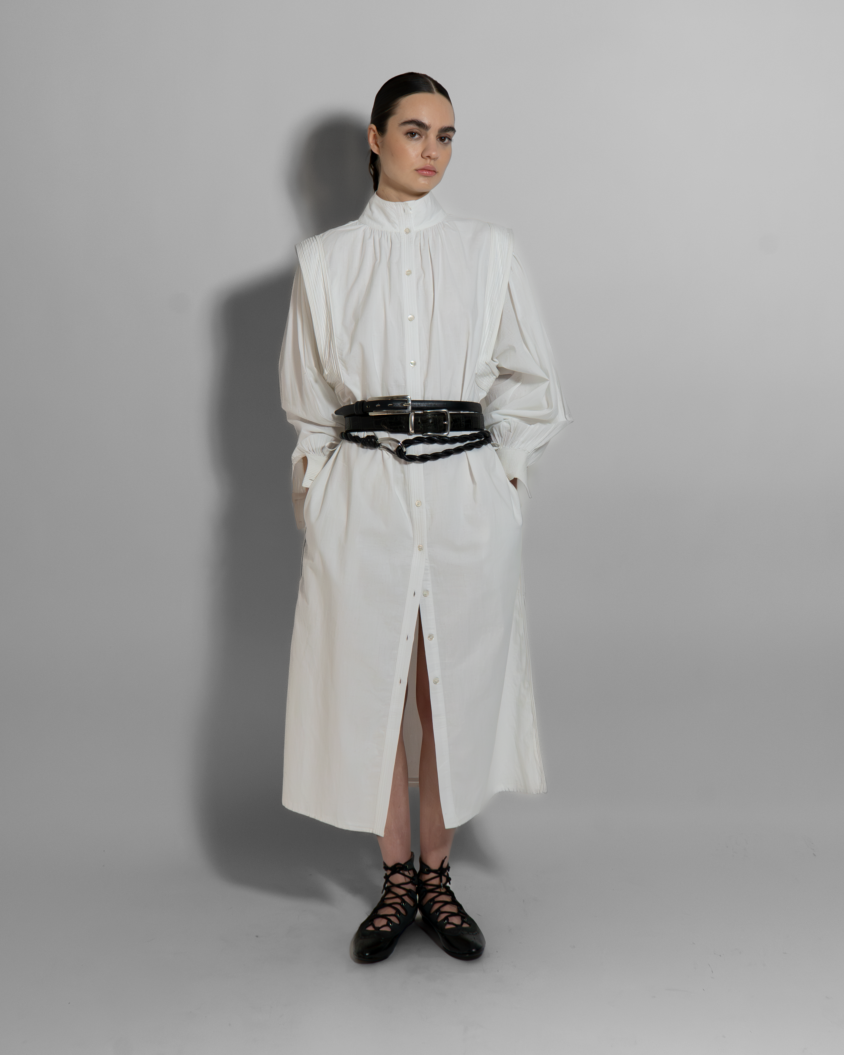 White cotton voile MAY dress with hand-embroidered details, black belt, long sleeves, and architectural cut for modern minimalist style