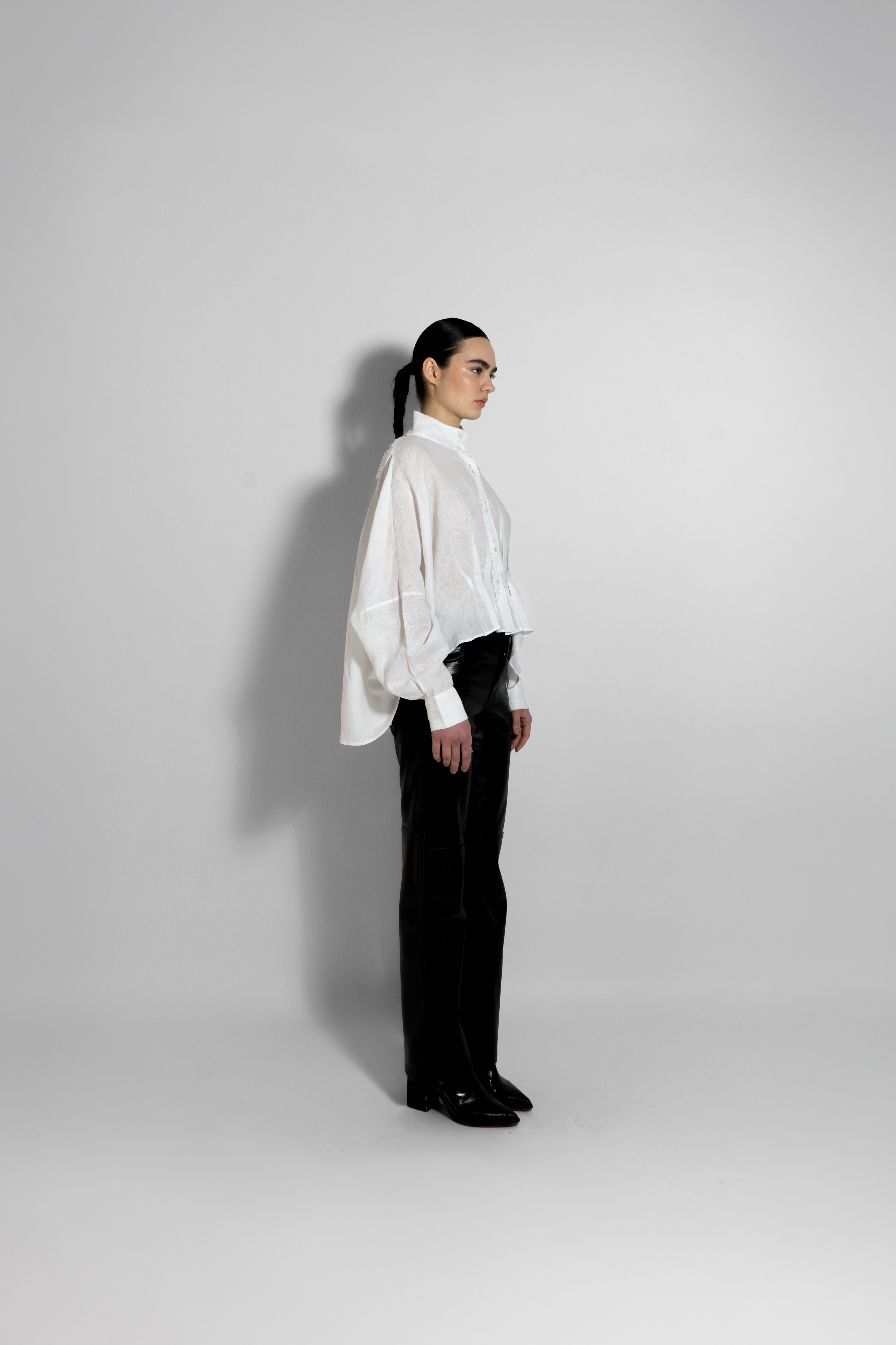 Side view of white sculpted blouse with minimalist black and white outfit