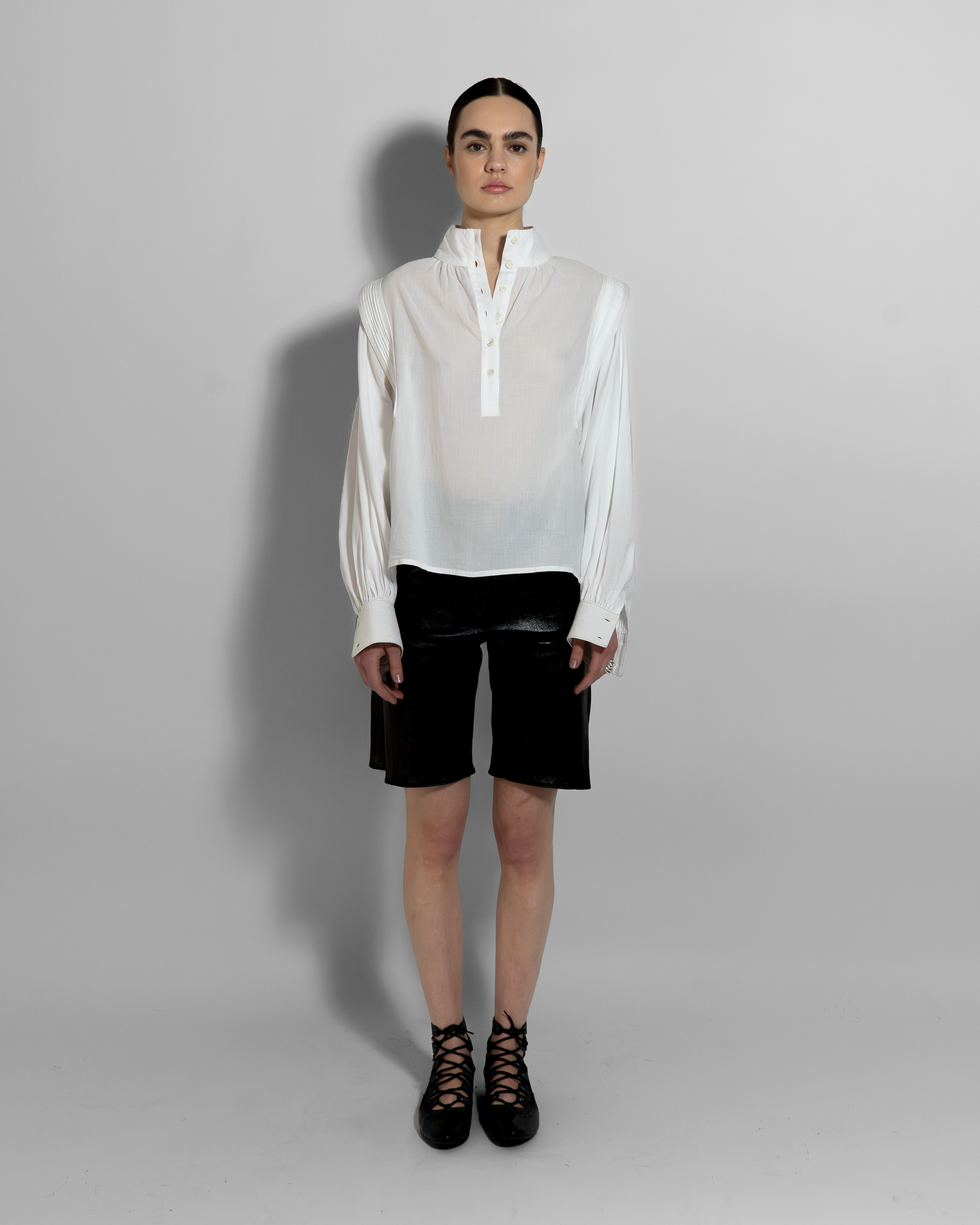 MAY white cotton voile blouse with sculptural oversized sleeves and hand-stitched details paired with black shorts