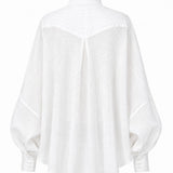 Cate shirt in soft white linen with sculptural pleats, generous silhouette, and handmade cuff details by Aymone Studio